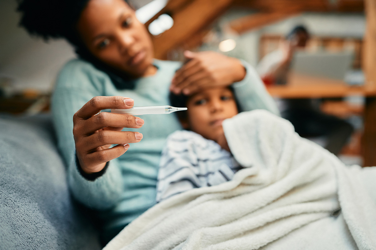 Child blowing her nose while her mother looks concerned.