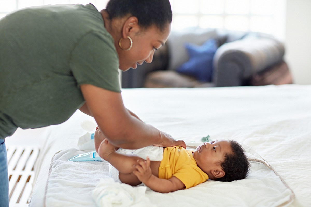 Mother changing her baby's diaper at home.