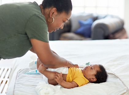 Mother changing her baby's diaper at home.