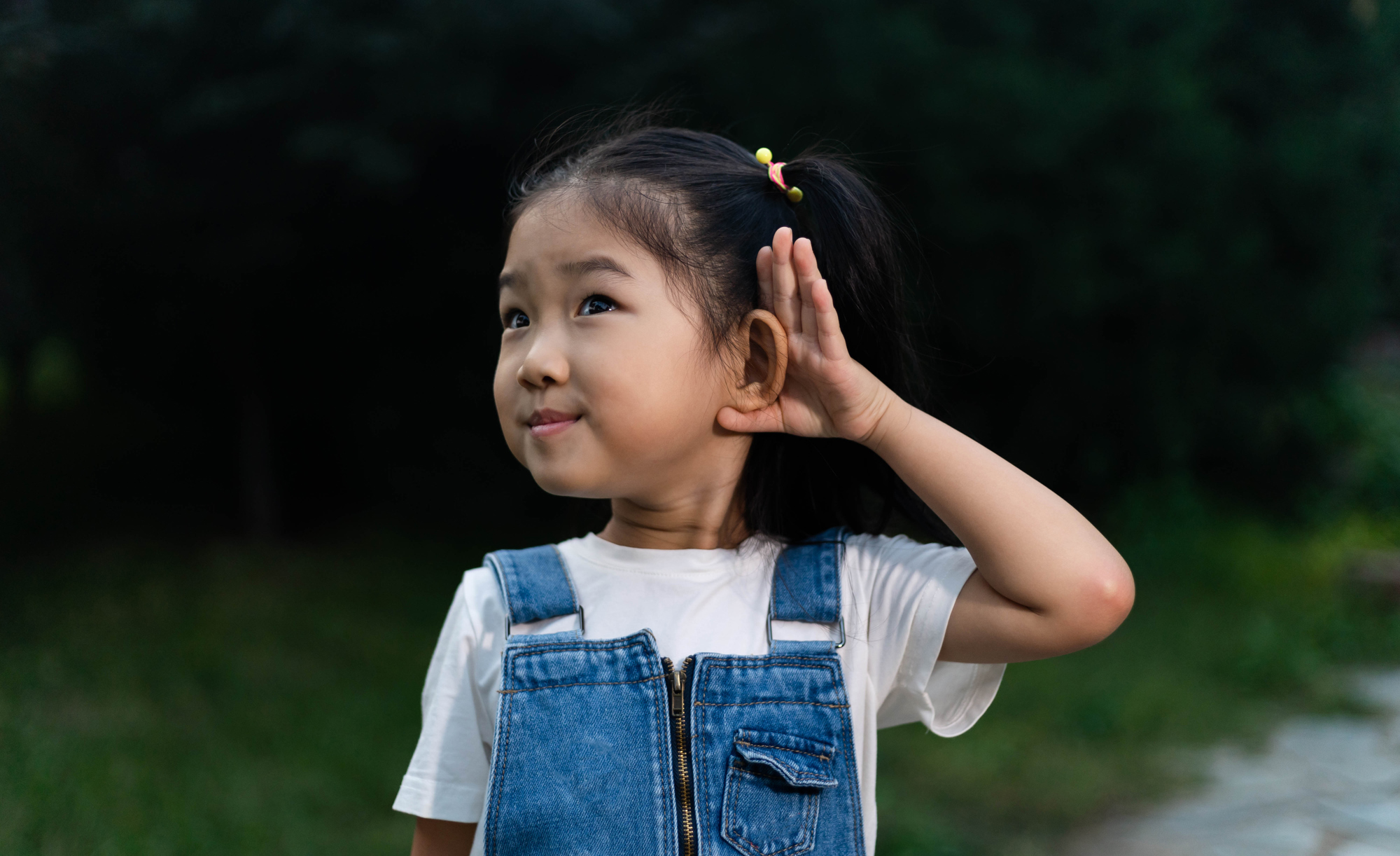 Girl holds her hand up to her ear to listen.