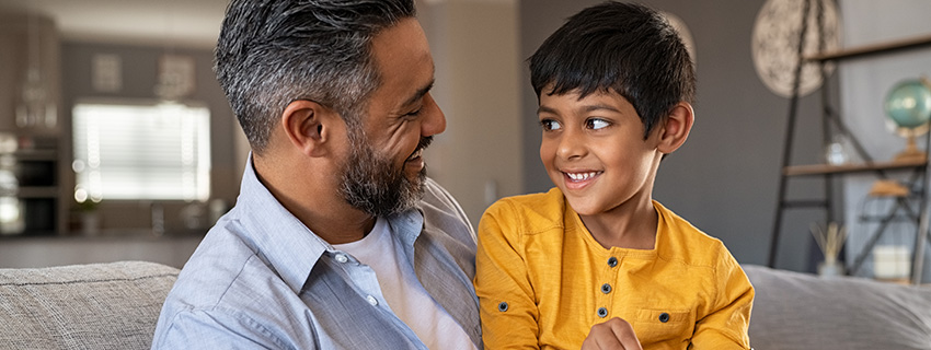 Dad and son smile at each other.