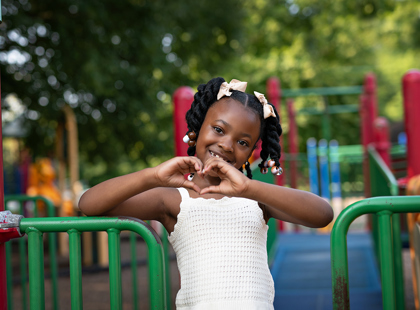 Patient Blessyn Watford making a heart with her hands on the playground.