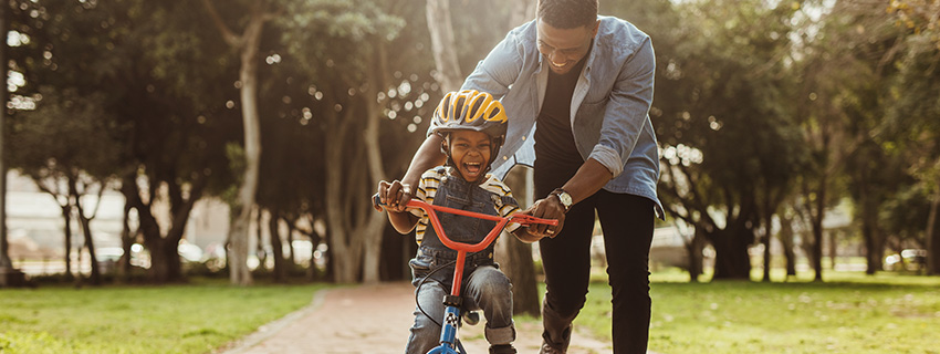 Dad teaches son to ride bike.