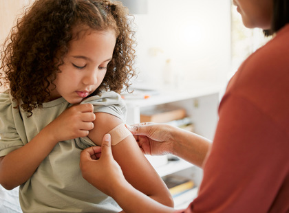 Nurse putting a bandage on a child who was just vaccinated.