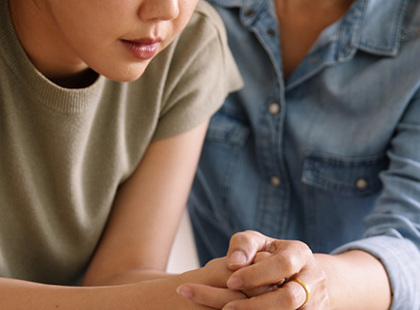 Close up of mother holding daughters hands to offer comfort her