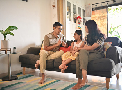 Parents sitting on a sofa and having a serious discussion with their daughter