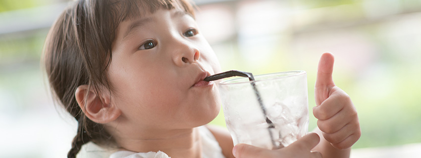 Child drinking a glass of water with thumbs up