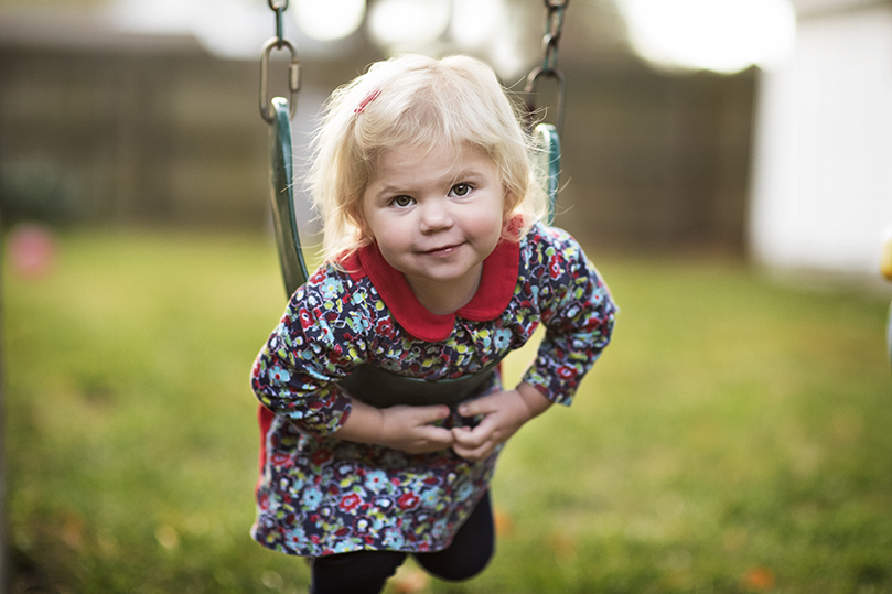 Laney Lion smiling on a swingset.