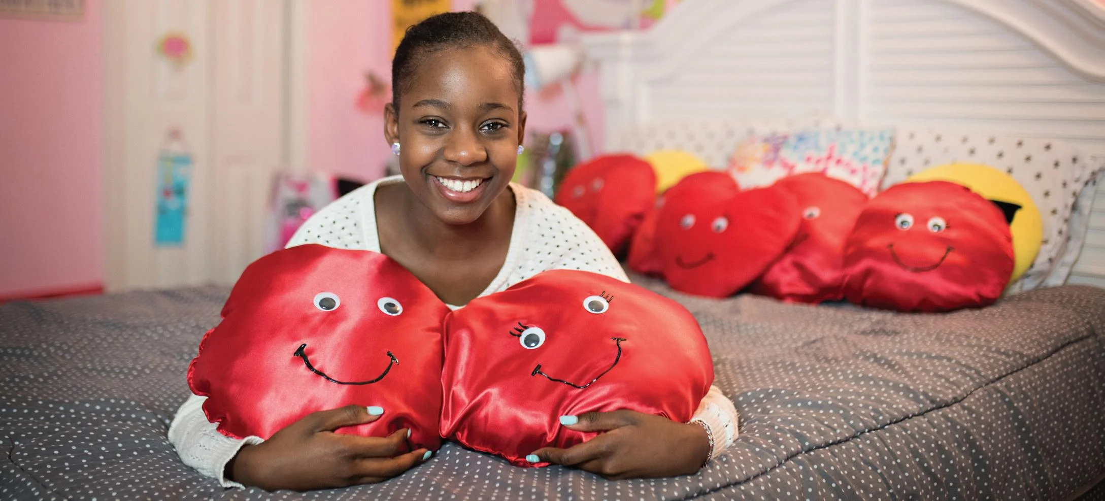 Ayana holding her "Ayana's Hope Cells" pillows